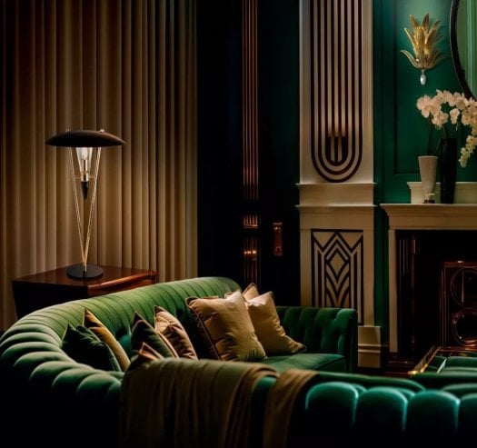 Designer lighting featuring a brass table lamp and brass wall light styled in a luxurious contemporary living room interior.