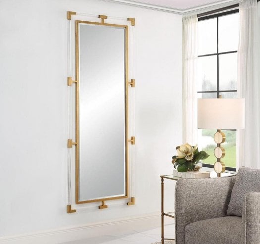 Large rectangular wall mirror with a slim gold frame, styled in a bright contemporary living room interior.