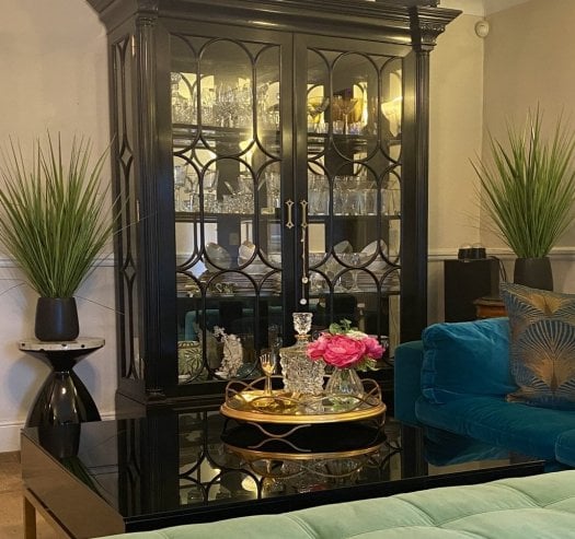 Luxury living room furniture featuring a Jonathan Charles display cabinet, modern sofa, coffee table, side table and gold round glass tray in an elegant designer interior.