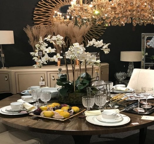 Luxury dining room furniture featuring a large round dining table, sideboard, statement chandelier and elegant dining accessories in a designer dining room setting.