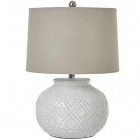 Squat white beaded ceramic table lamp featuring a rounded textured base with raised diamond detailing, neutral linen shade and silver finial.